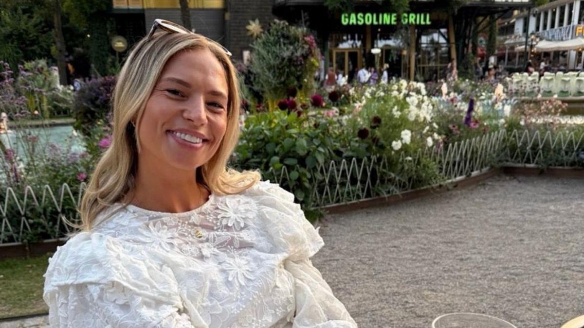 Ella smiling at the camera. She has long blonde hair, she is wearing a white flowery top and she's sat outside on a night out