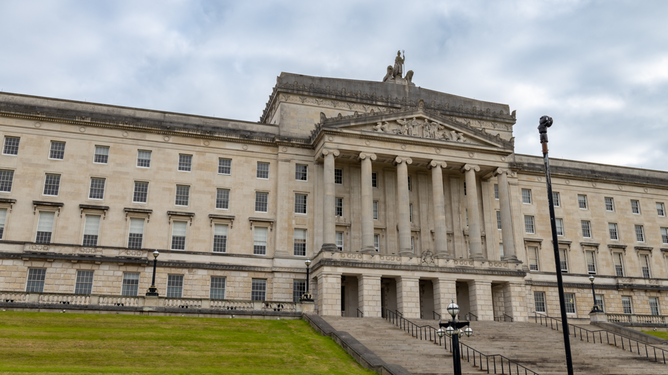 Stormont parliament building on a cloudy day. Six pillars are above the entrance and steps led up to the door.