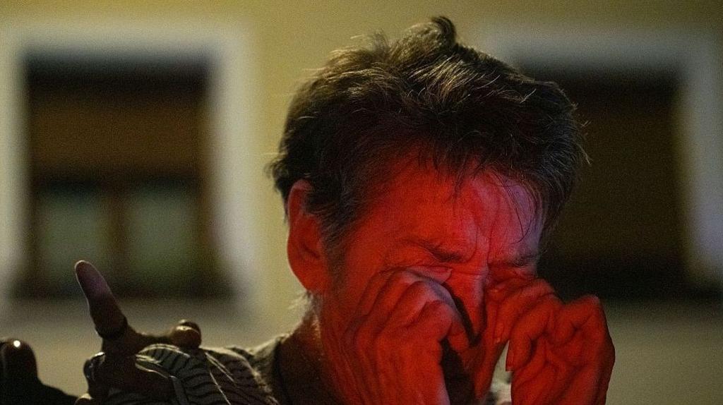 Maricarmen covers her eyes as she weeps