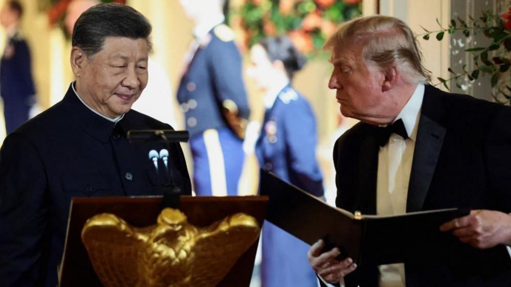 US President Donald Trump holds a binder as he stands next to Chinese President Xi Jinping before Xi delivers a speech during a state dinner at the White House in Washington