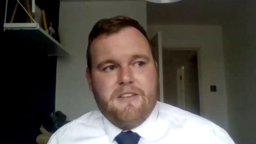 Jack Kay pictured in a white shirt and dark blue tie.