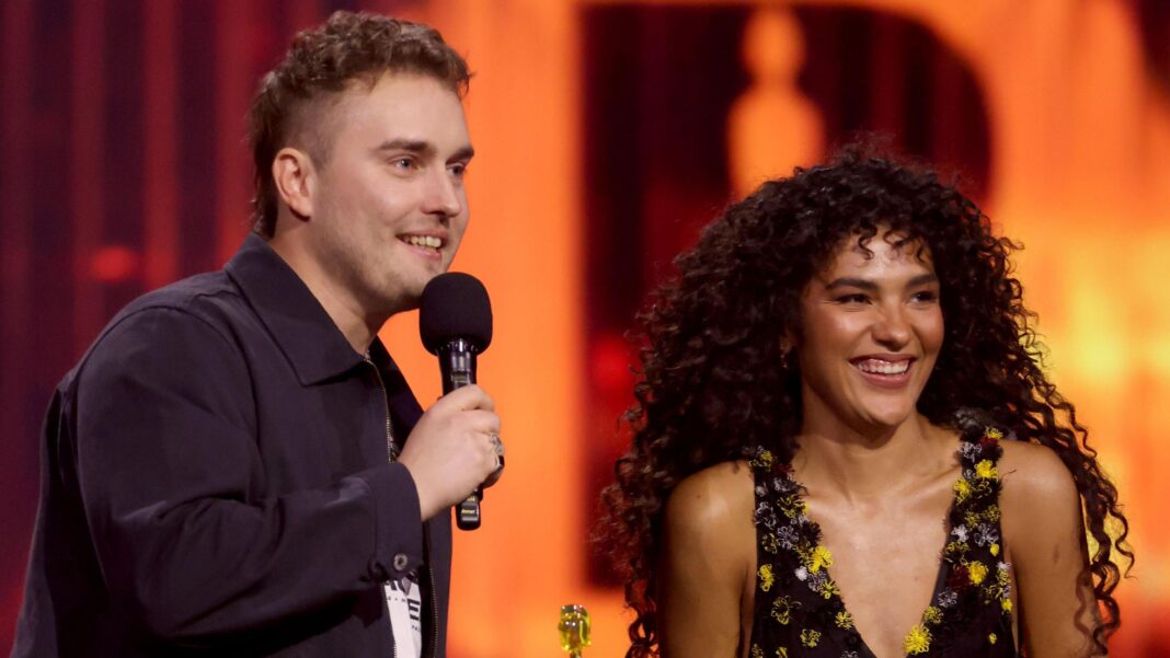 Ella Langley’s Choosin’ Texas becomes longest-running number one in US chart history Sam Fender and Olivia Dean speaking and smiling on stage at the Brit Awards