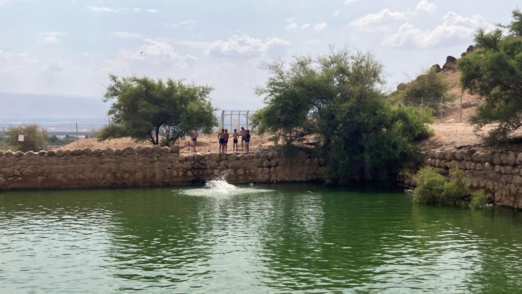 Israeli settlers stand beside Herod's Pool, which they have set up as a swimming pool this summer with water diverted from a Palestinian village, in the Jordan Valley, in the occupied West Bank