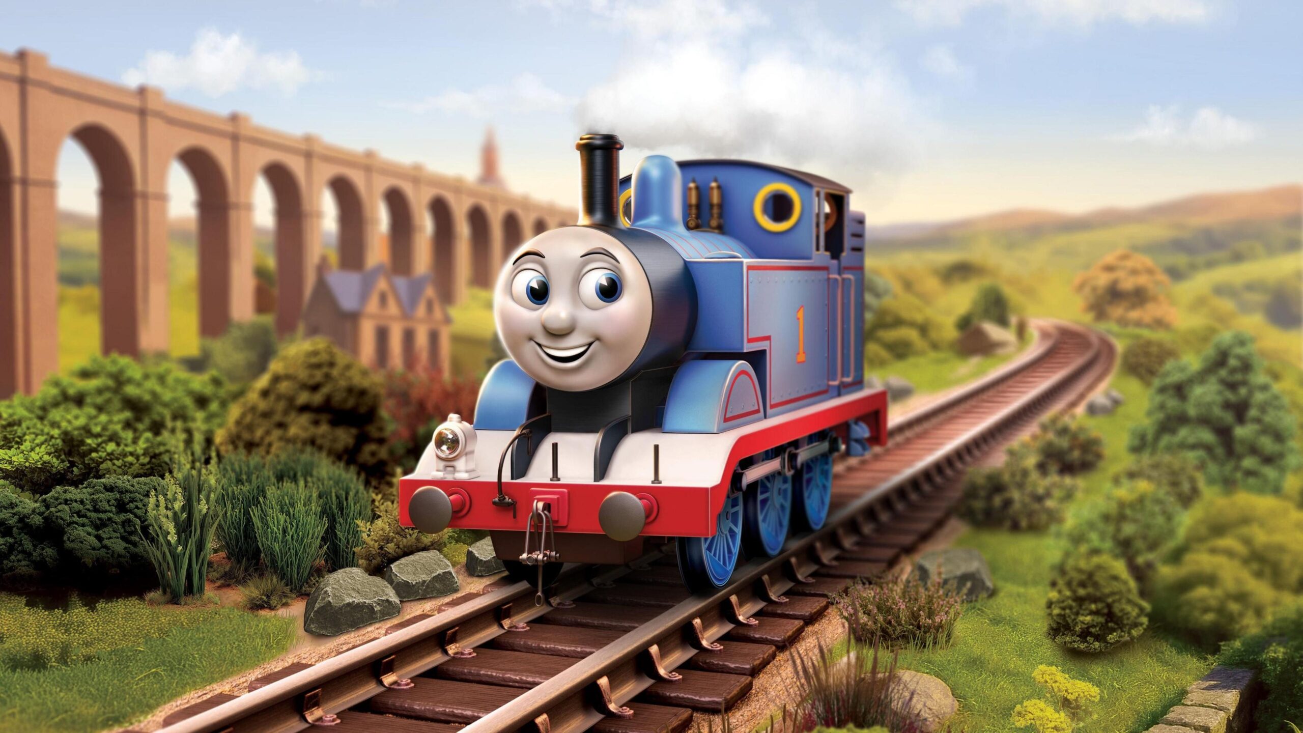 A screenshot showing the new look Thomas The Tank Engine as he returns to 3D. He is smiling on a sunny railway with an aqueduct behind him.