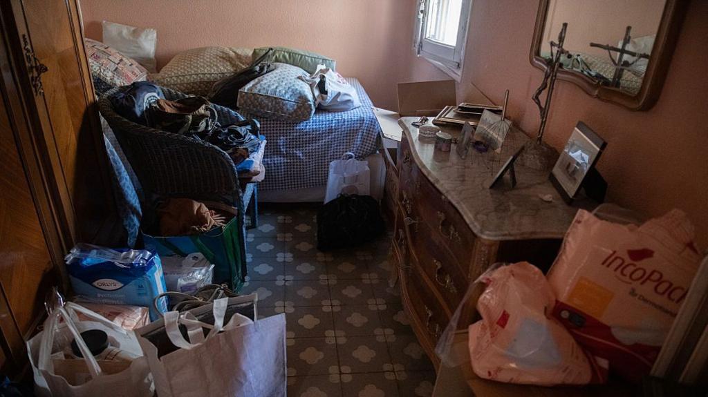 Bags of belongings stand inside a flat