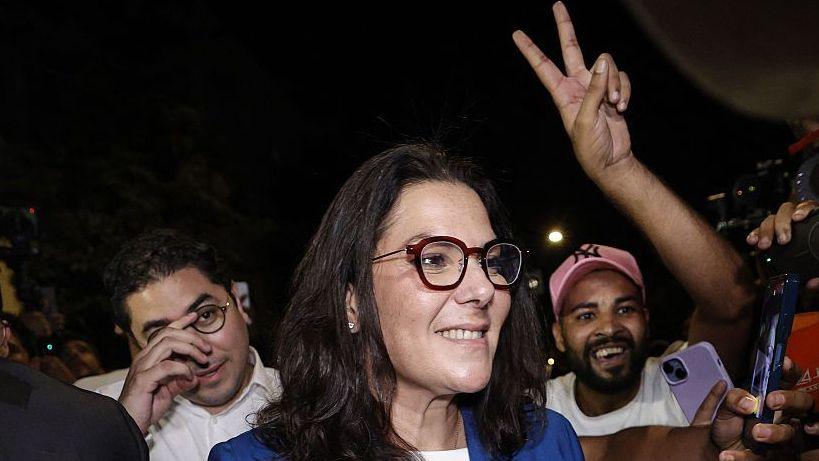 Fatima Zahra El Mansouri wearing a blue blazer over a white shirt. She is surrounded by celebrating crowds of men after the announcement of the provisional results of the legislative elections in the early hours of 24 September 2026.