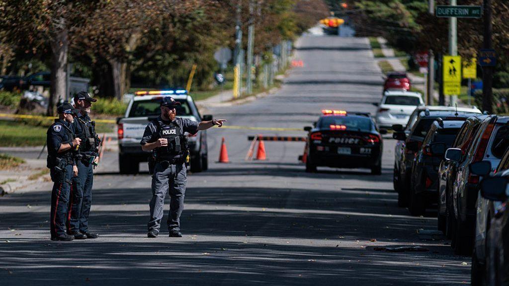 A forensics officer points towards a police vehicle (out of frame) at the scene of a shooting the Sons of Jacob Synagogue where a man armed with a shotgun exchanged gun fire with a police officer stationed outside of the Synagogue late Sunday evening as people were arriving for Yom Kippur.