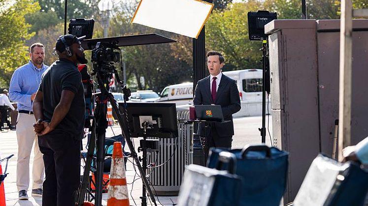 Camera crew and reporter set up on a street corner in Washington DC
