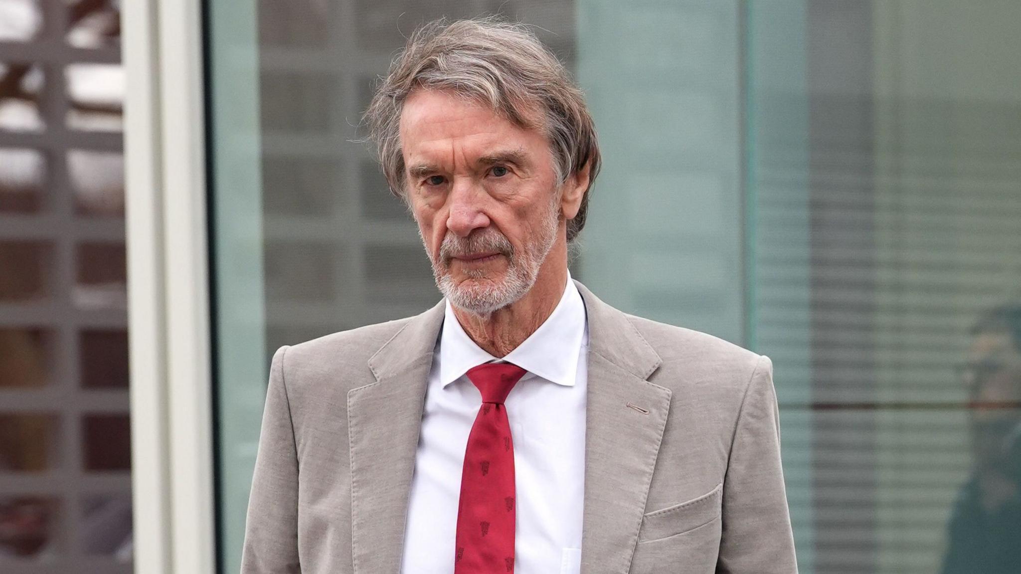 Sir Jim Ratcliffe in light-coloured smart jacket, white shirt and red tie