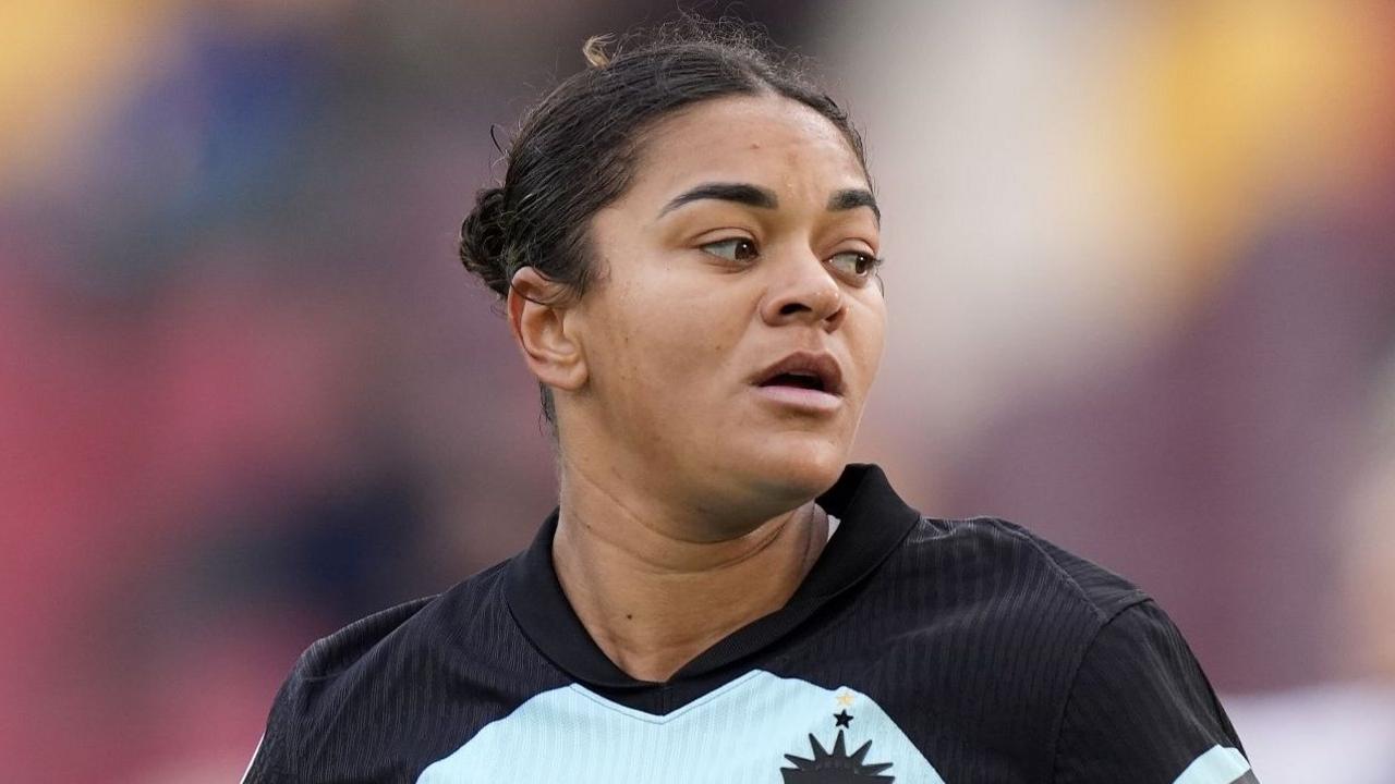 Jess Carter wearing the light blue Gotham FC strip, which has black shoulders. She is warming up ahead of a match and has her dark hair in a bun.