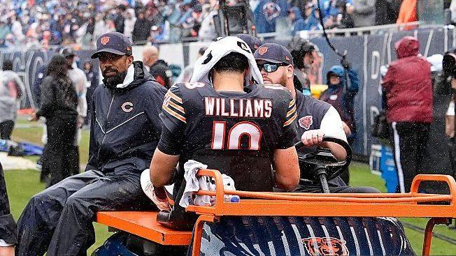 Caleb Williams has a towel over his head and sits on a buggy as he's driven off the field injured playing for the Chicago Bears