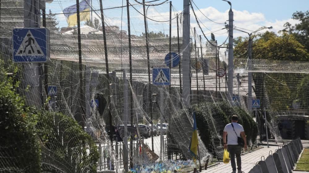 A man crosses a street covered with an anti-drone net, amid Russia's attack on Ukraine, in the frontline city of Kramatorsk