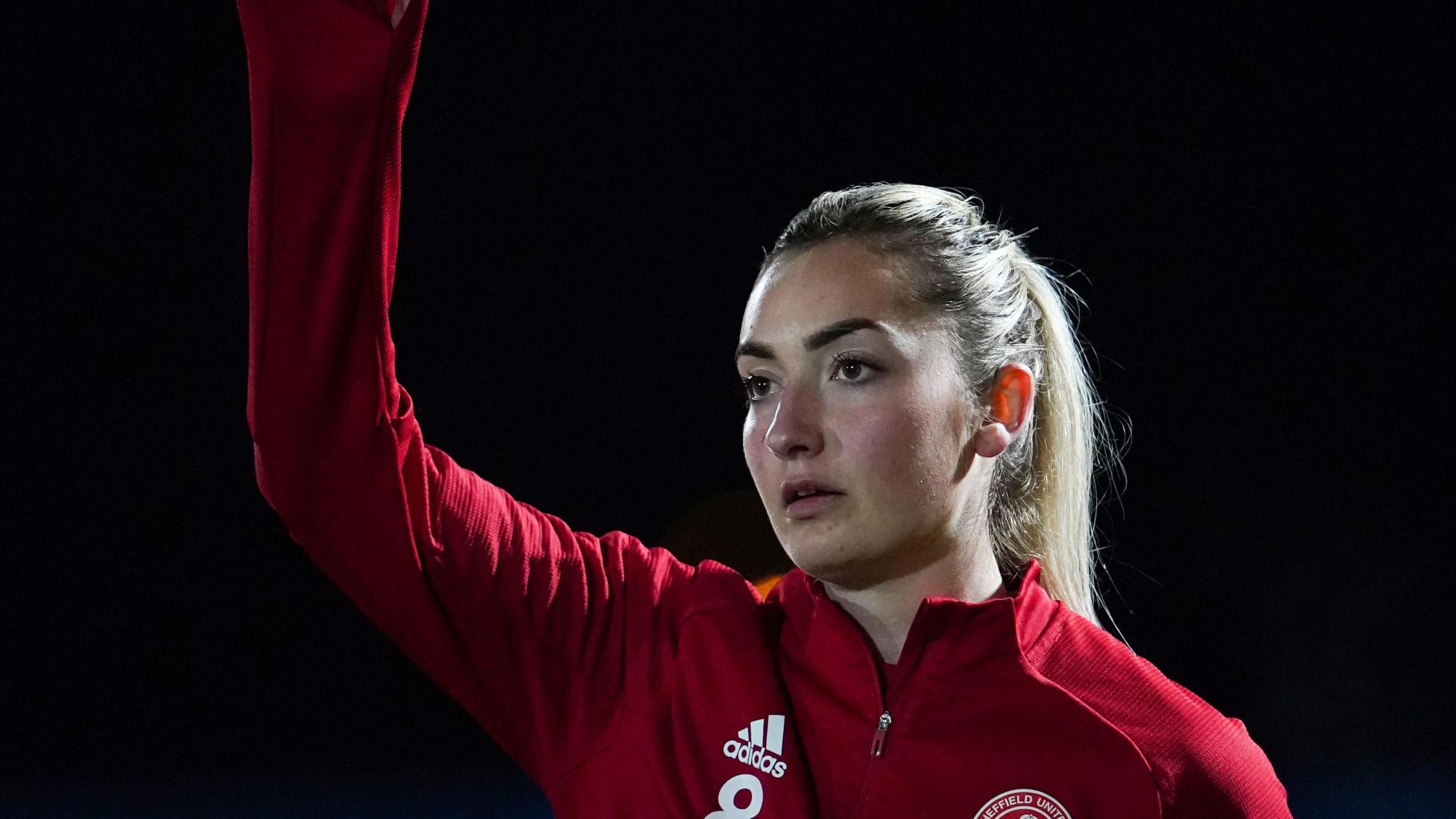 Maddy Cusack in a red Sheffield United jacket with her arm in the air