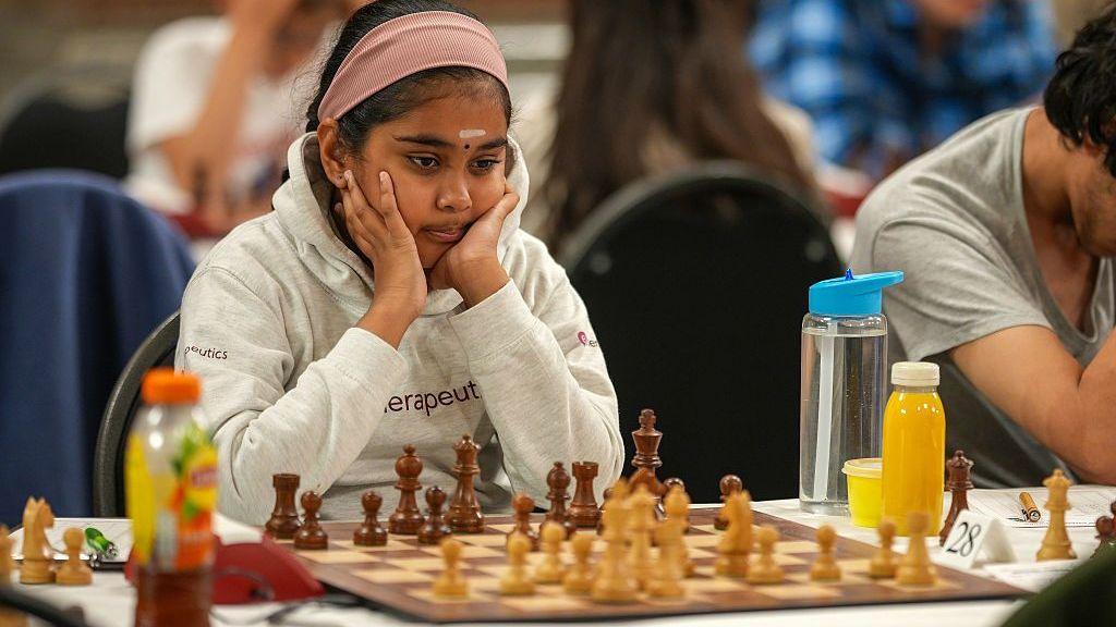 Bodhana Sivanandan, in a grey hoody, rests her face in her hands as she looks at a chess board in front of her