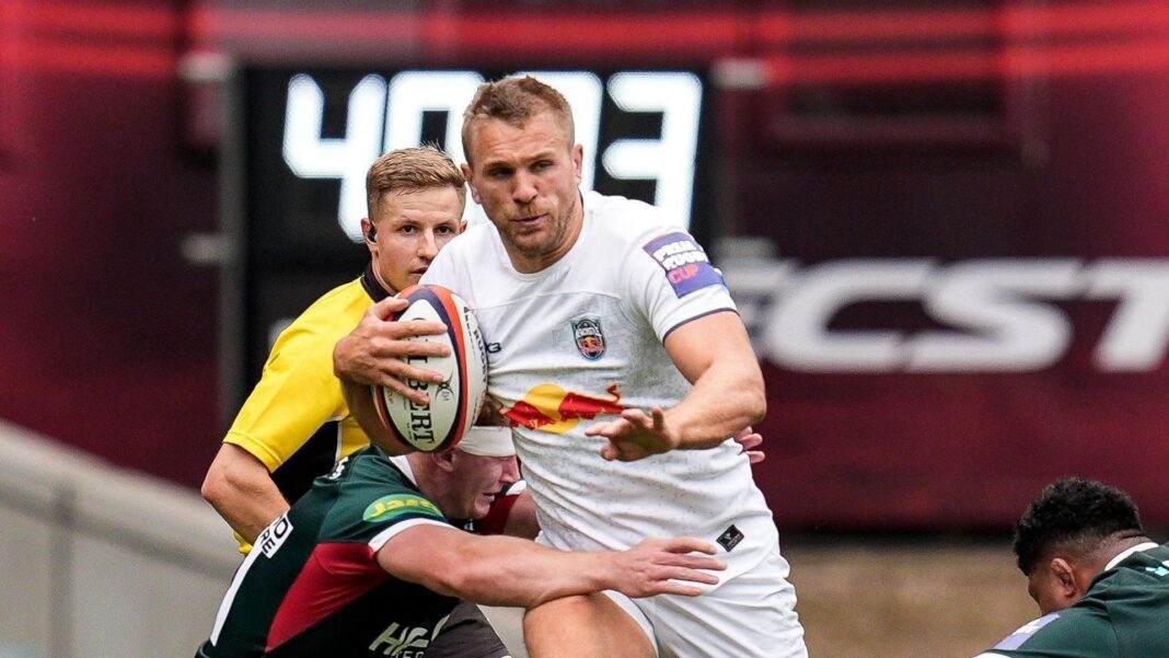 Chris Harris runs with the ball tucked under his right arm while being tackled around the waist during Newcastle's Prem Rugby Cup game with Leicester