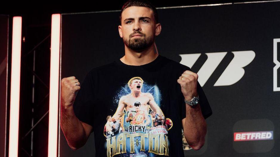 John Hedges holds up his fists and is wearing a black t-shirt with images of Ricky Hatton printed on it