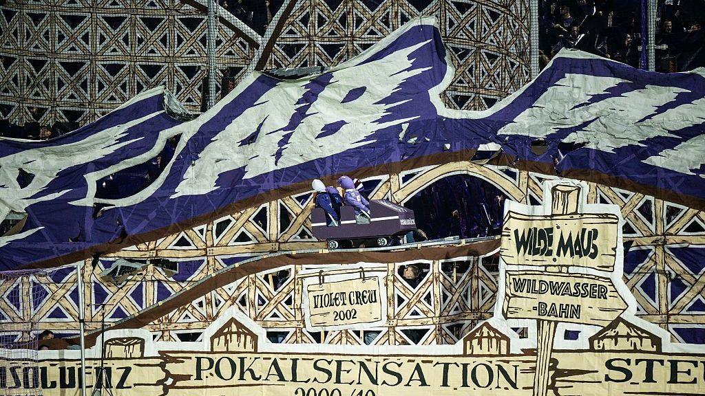 A tifo on display at VfL Osnabruck stadium, showing a rollercoaster cart on a track with dummies inside