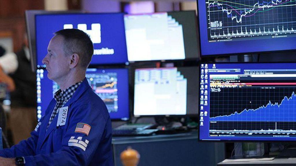 A stock market trader monitors screens on the stock market