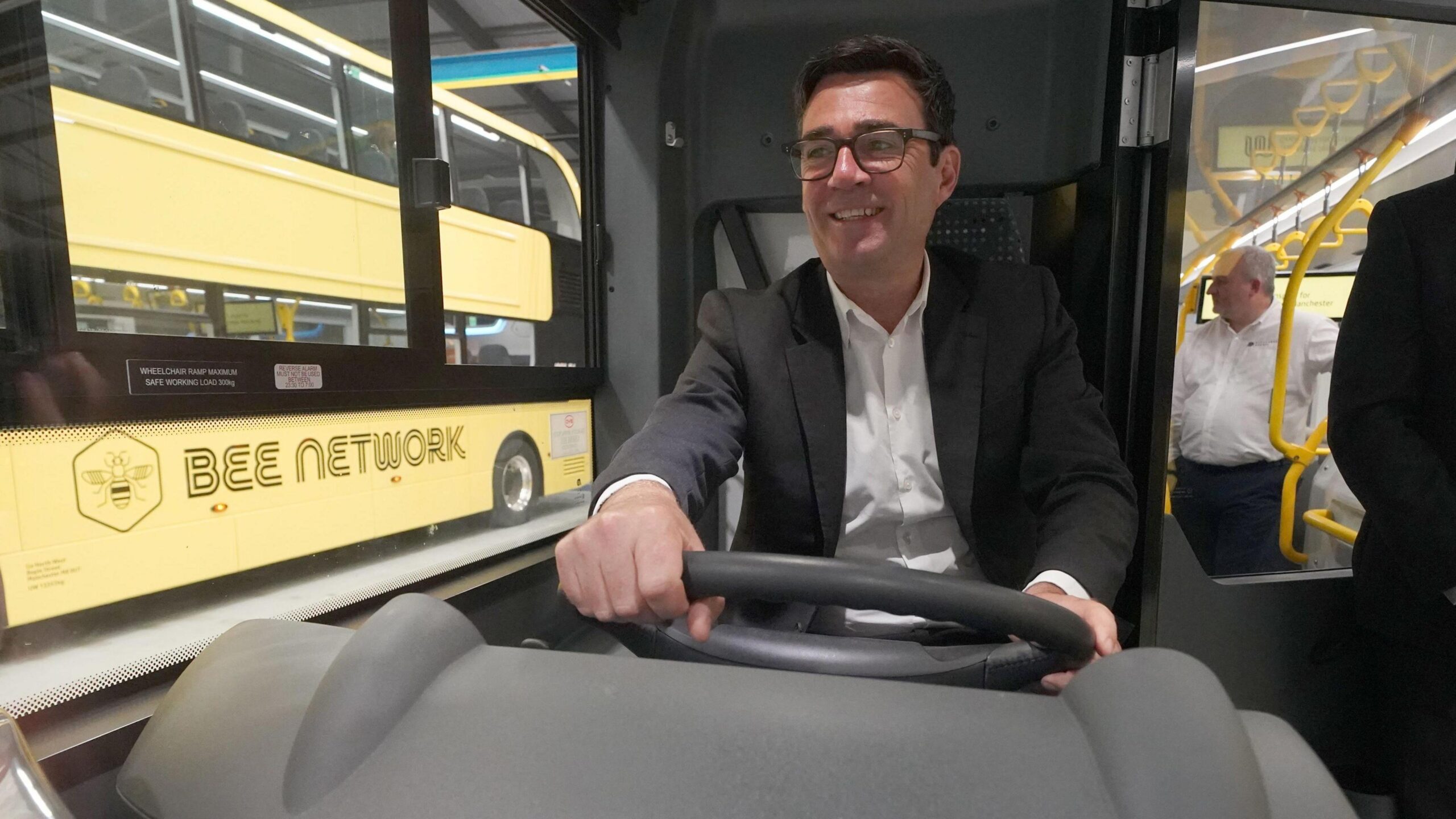 Andy Burnham drives a yellow "Bee Network" branded bus.