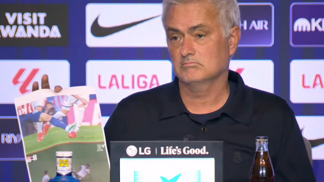 A frowning Jose Mourinho at his news conference with screenshots of incidents he believed should have brought about red cards for Atletico Madrid players. In the background is an advertising board featuring sponsor and competition logos.