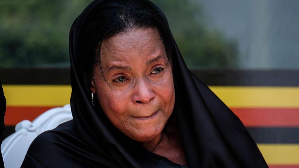 Best Kemigisa dressed in black, with a black head covering draped over her shoulders, appearing emotional