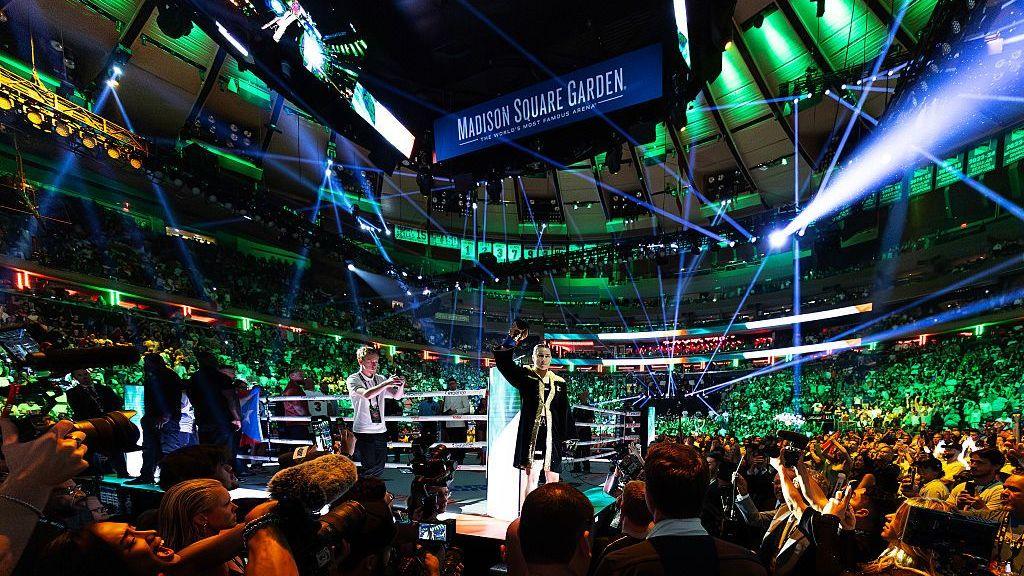 Katie Taylor stands on a ring apron at Madison Square Garden and raises her arm in the air