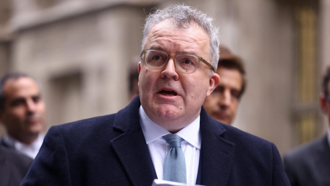 Tom Watson wearing a dark jacket and a light blue tie