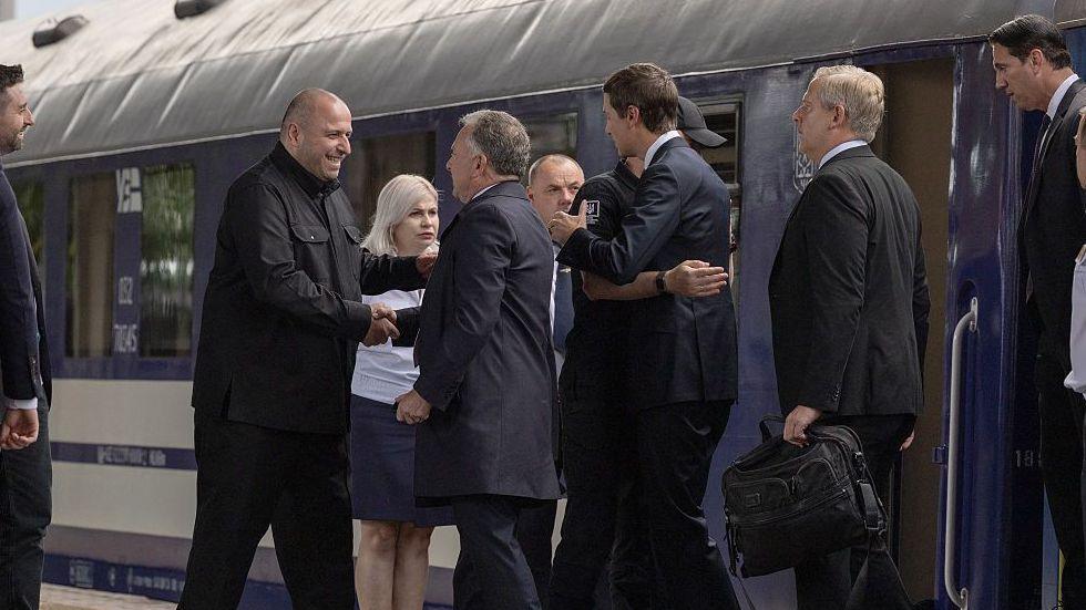 Witkoff and Kushner step off a train and shake the hands of officials waiting for them