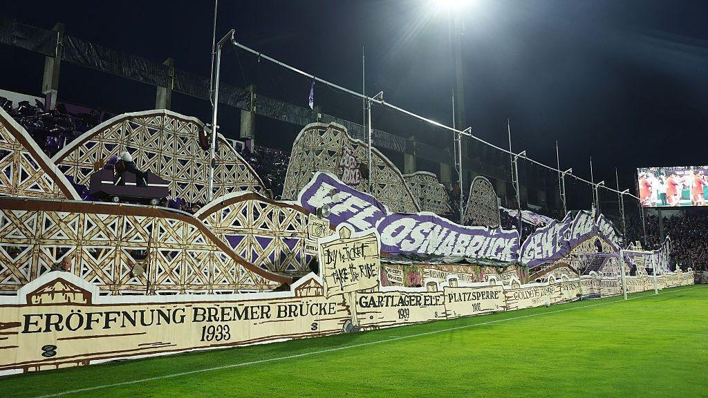 A tifo on display at VfL Osnabruck stadium, showing a rollercoaster cart on a track with dummies inside