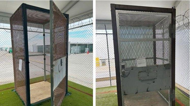 A metal cage sits within a larger cage that has razor wire across the top. The small cage has a door with a combination lock