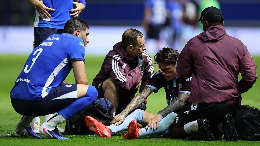 Alejandro Garnacho is attended to by officials as he sits on the pitch