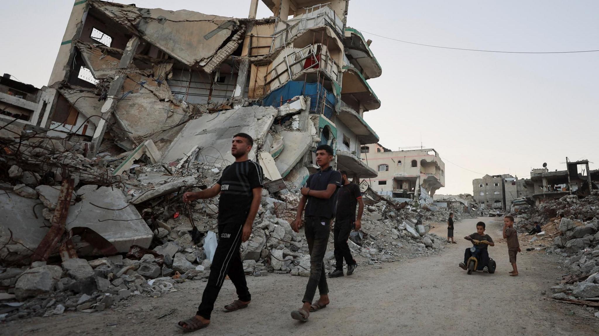 Palestinians walk past the rubble of destroyed buildings in Gaza City, northern Gaza (22 September 2026)