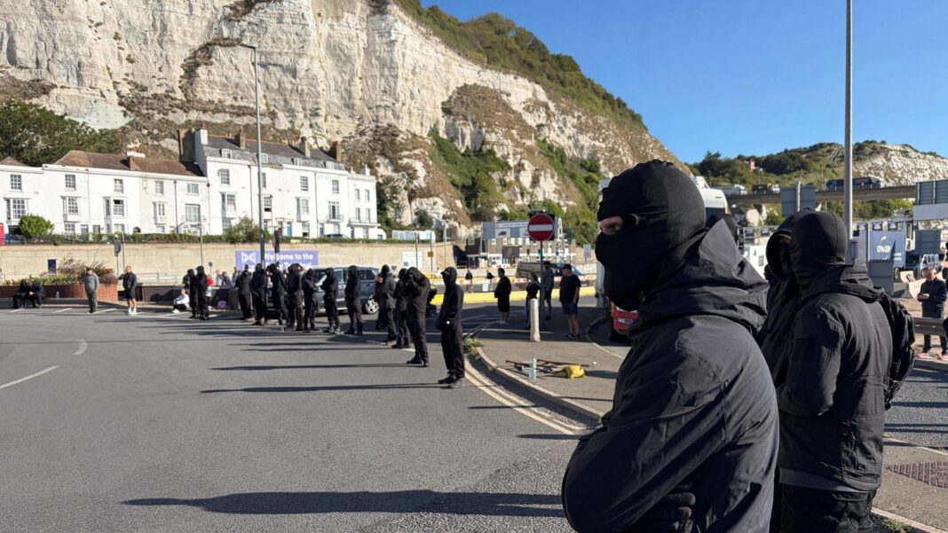 A row of masked men block a road at the entrance to the Port of Dover.