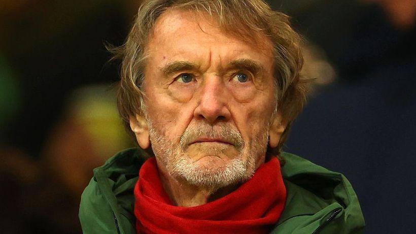 Sir Jim Ratcliffe in a green coat and red scarf