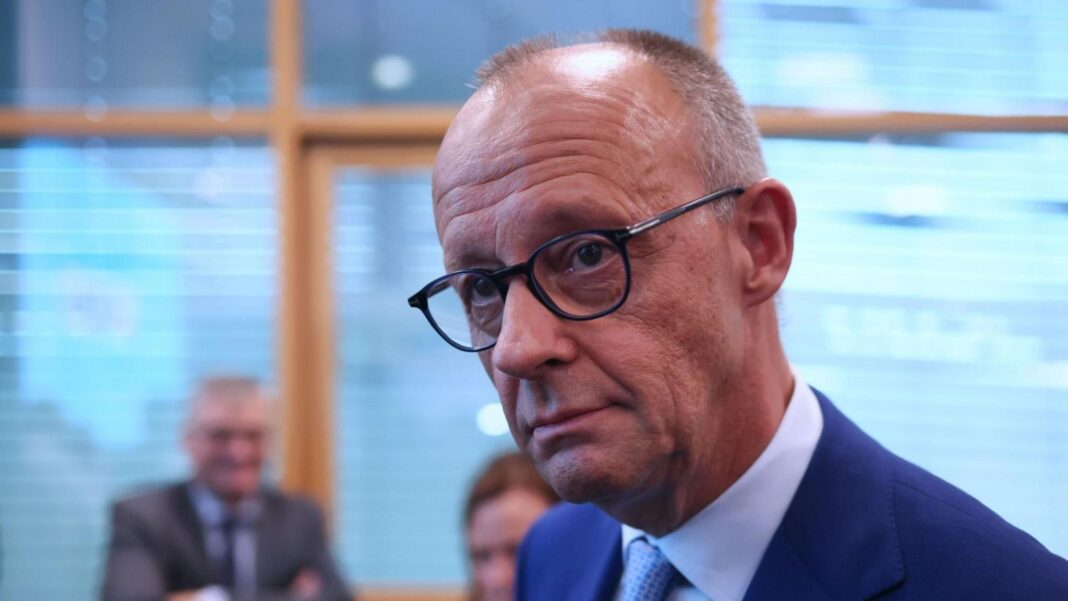 Merz vows to keep coalition together for Germany’s ‘democratic future’ Friedrich Merz, wearing black-rimmed glasses and a blue suit, looks just off camera.
