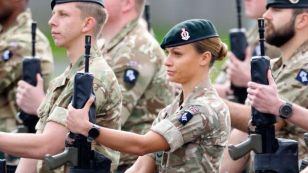 Junior officers in the Royal Army Medical Corps holding rifles and dressed in camouflage.