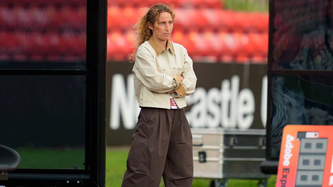 Jackie Bachteler stands with arms folded, wearing a cream jacket and brown trousers