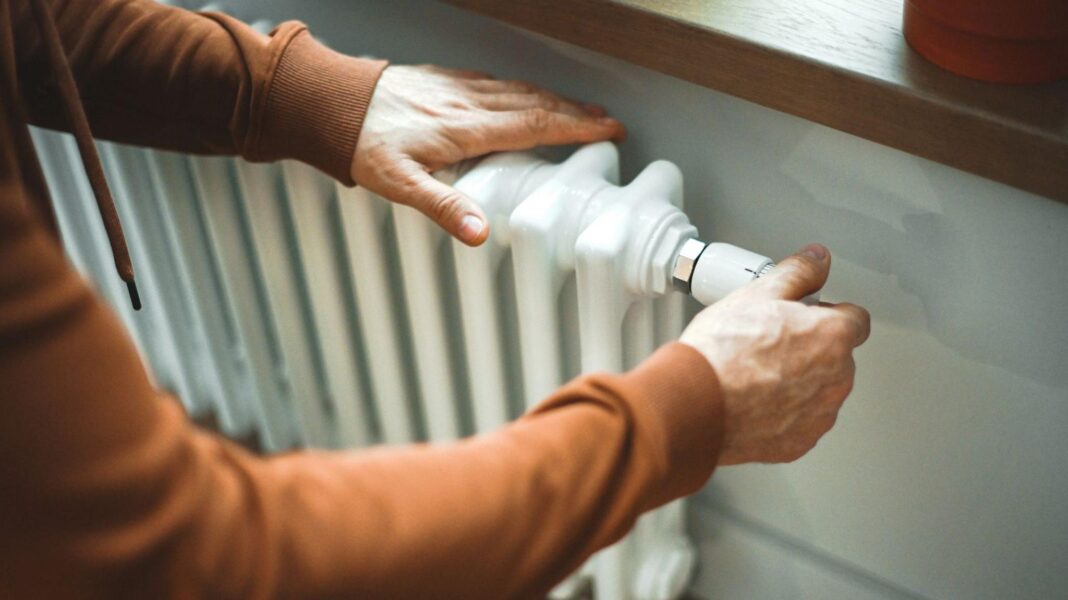 Two hands on a white radiator.