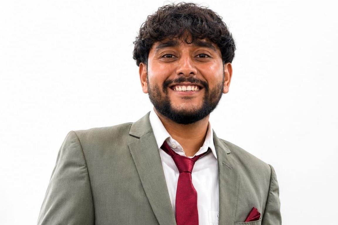 A close up shot of Purvansh Parmar wearing a gray coat, white shirt and a red tie