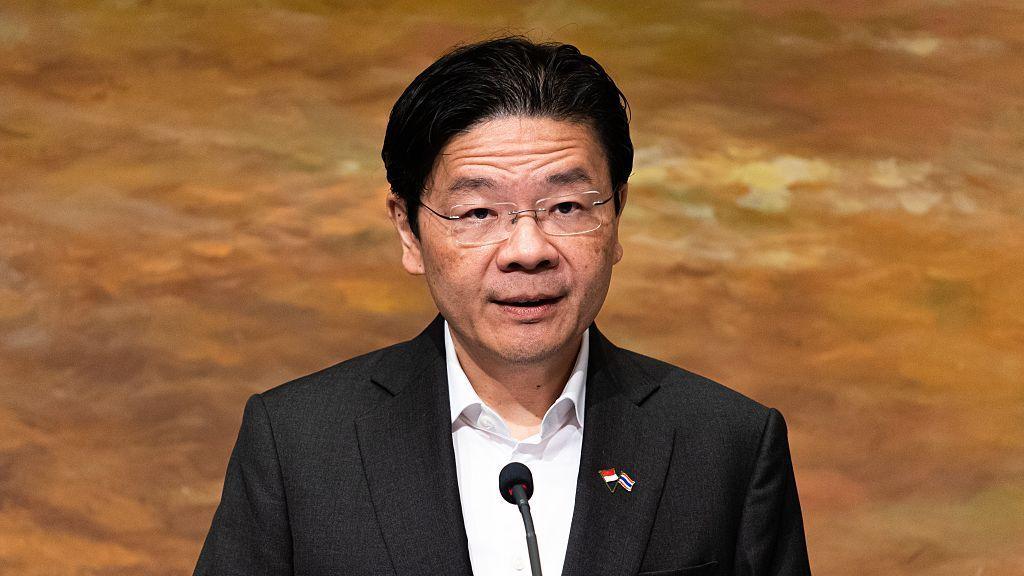 Highest paid world leader to get salary increase of $1 million Lawrence Wong in a black suit and white shirt addresses a crowd on a podium