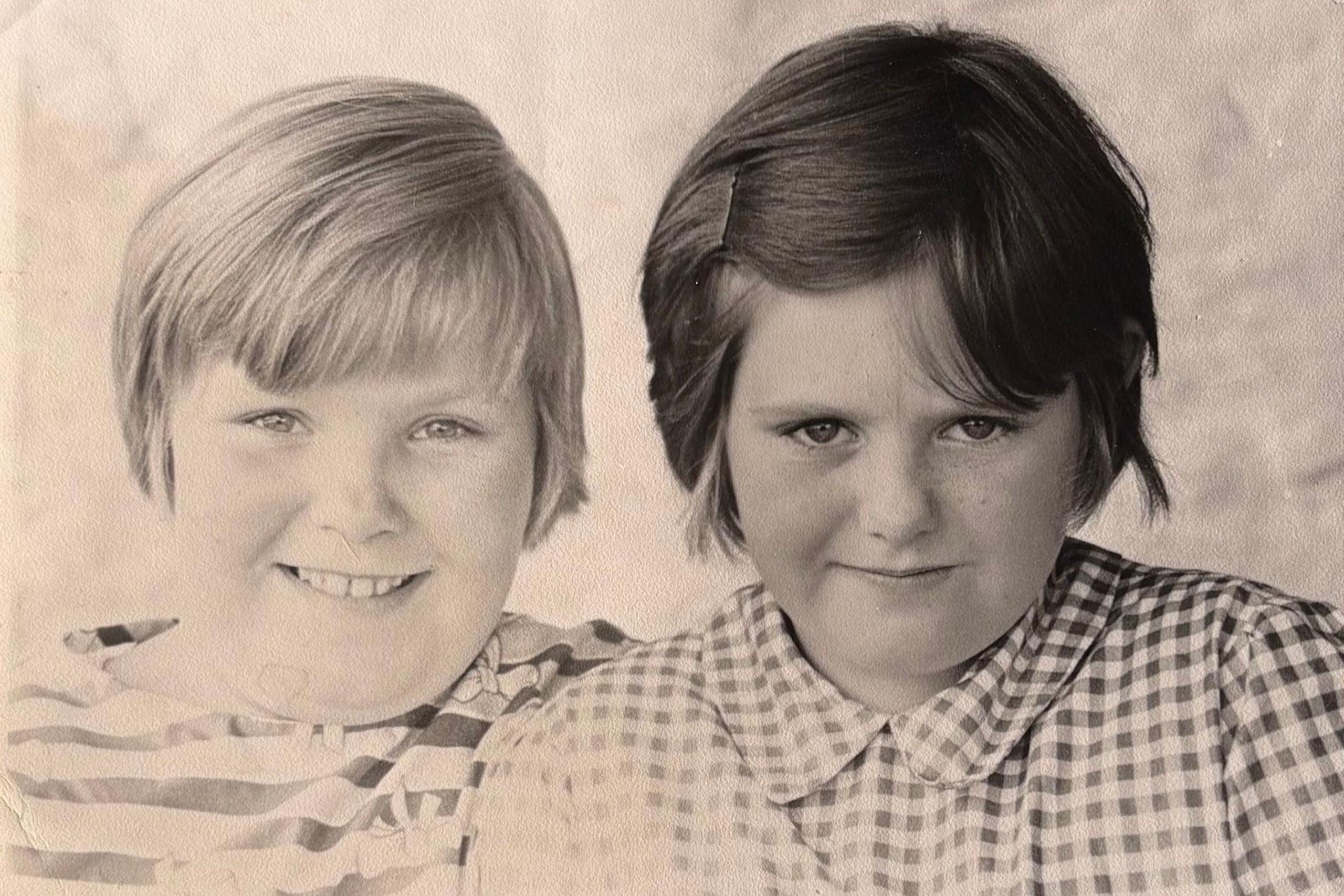 A black and white photograph showing two young sisters with short hair, smiling side by side
