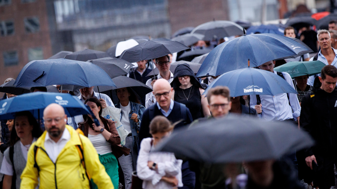 Commuters walking in the rain with umbrellas up