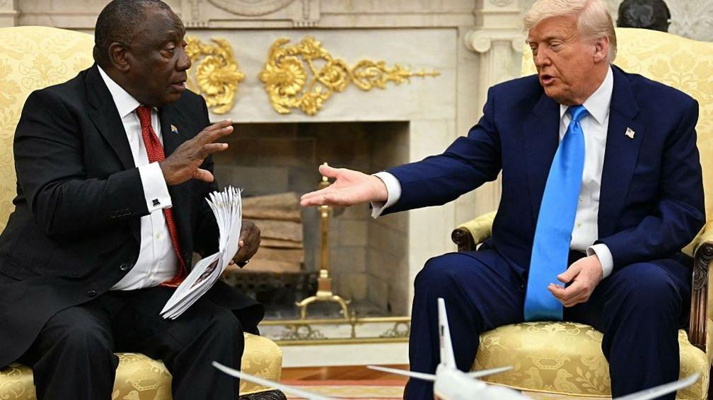 President Donald Trump hands papers to South African President Cyril Ramaphosa during a meeting in the Oval Office of the White House in Washington, DC, on 21 May, 2025.