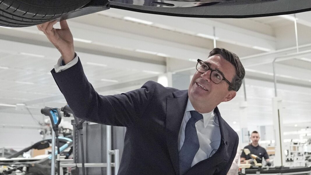 Prime Minister Andy Burnham looks at a car on the production line during a visit