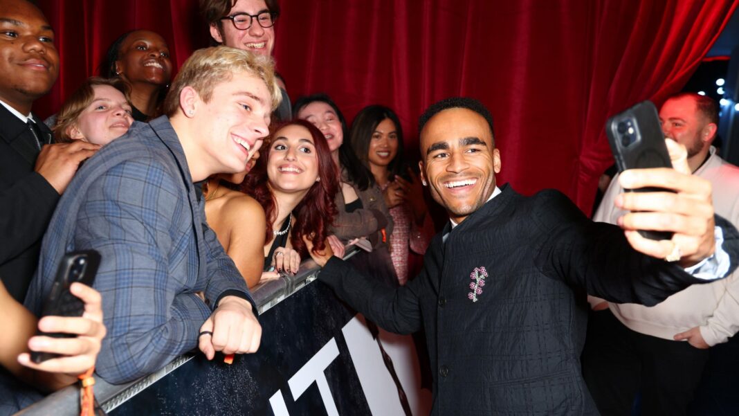 Why Munya Chawawa is ‘jumping ship’ from socials to Shakespeare Munya Chawawa smiling, holding a phone and taking a selfie with a group of fans on the other side of a barrier on the red carpet at a Brit Awards event in 2025