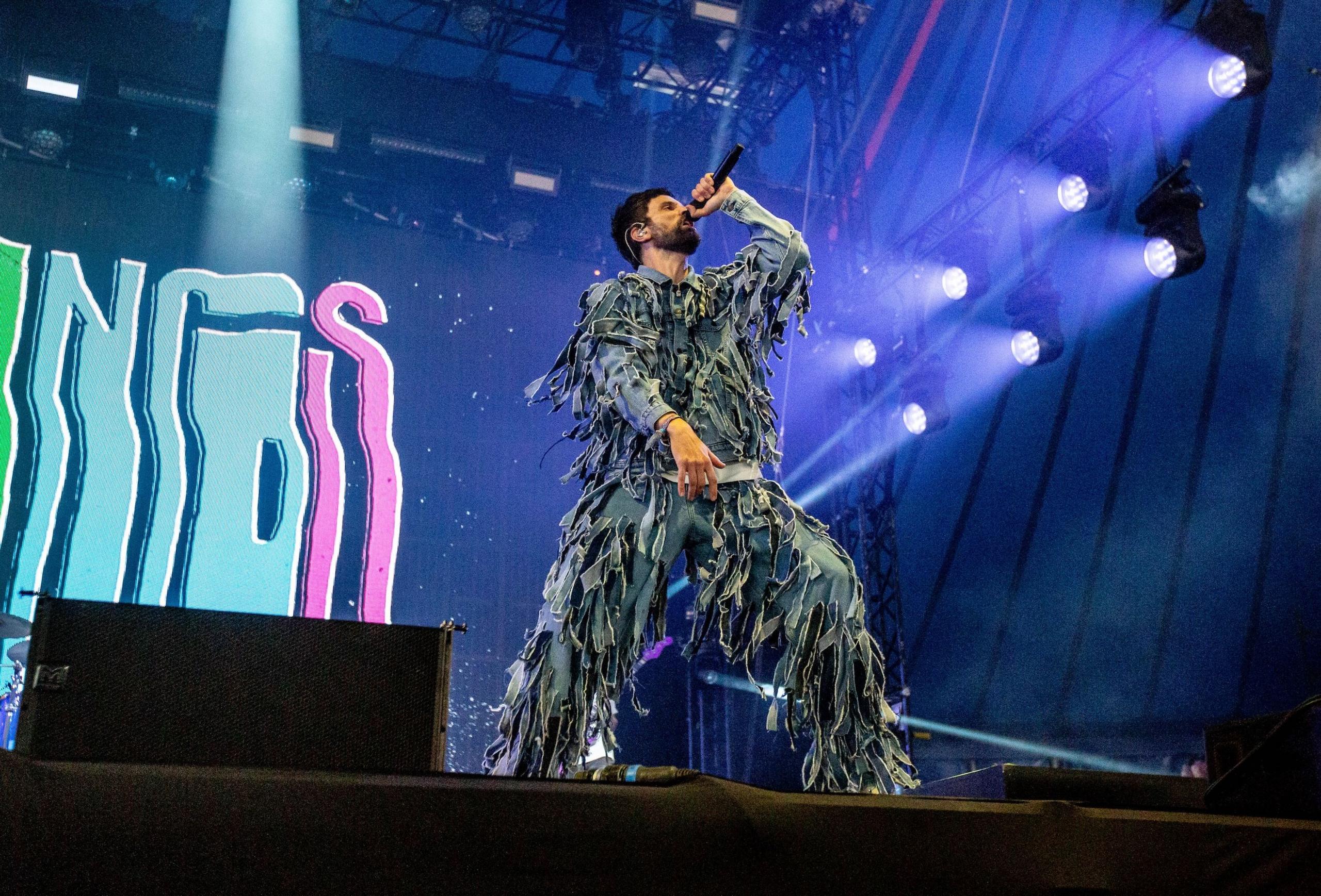 Kasabian play the Woodsies stage at Glastonbury, 2024. Serge is wearing a blue tasselled jumpsuit.