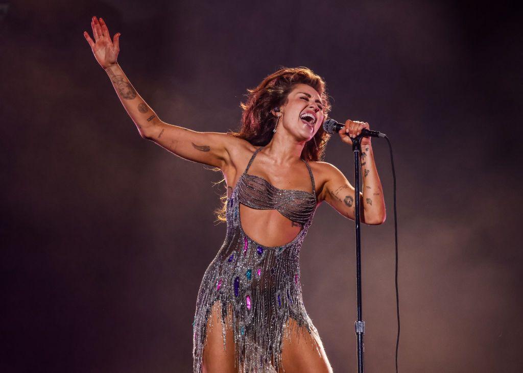 Miley Cyrus performing in silver glittering dress.