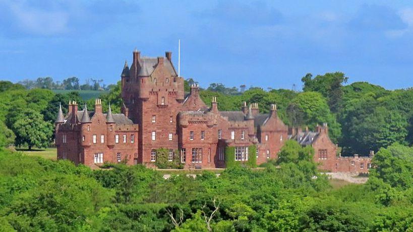 A view of Ayton Castle an impressive sandstone building with numerous turrets surrounded by trees