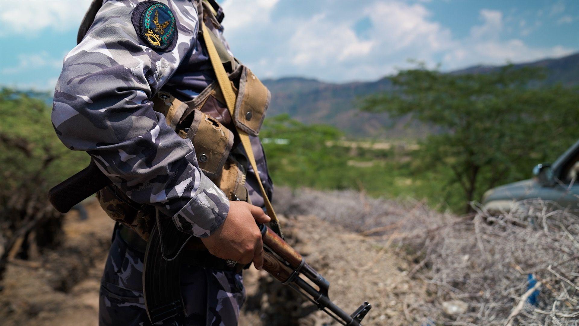 Yemeni government soldier stands in hills near the front line west of Taiz, holding an automatic rifle
