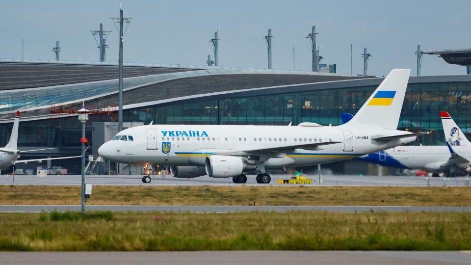 A white painted passenger plane sits on a runway at an airport after landing